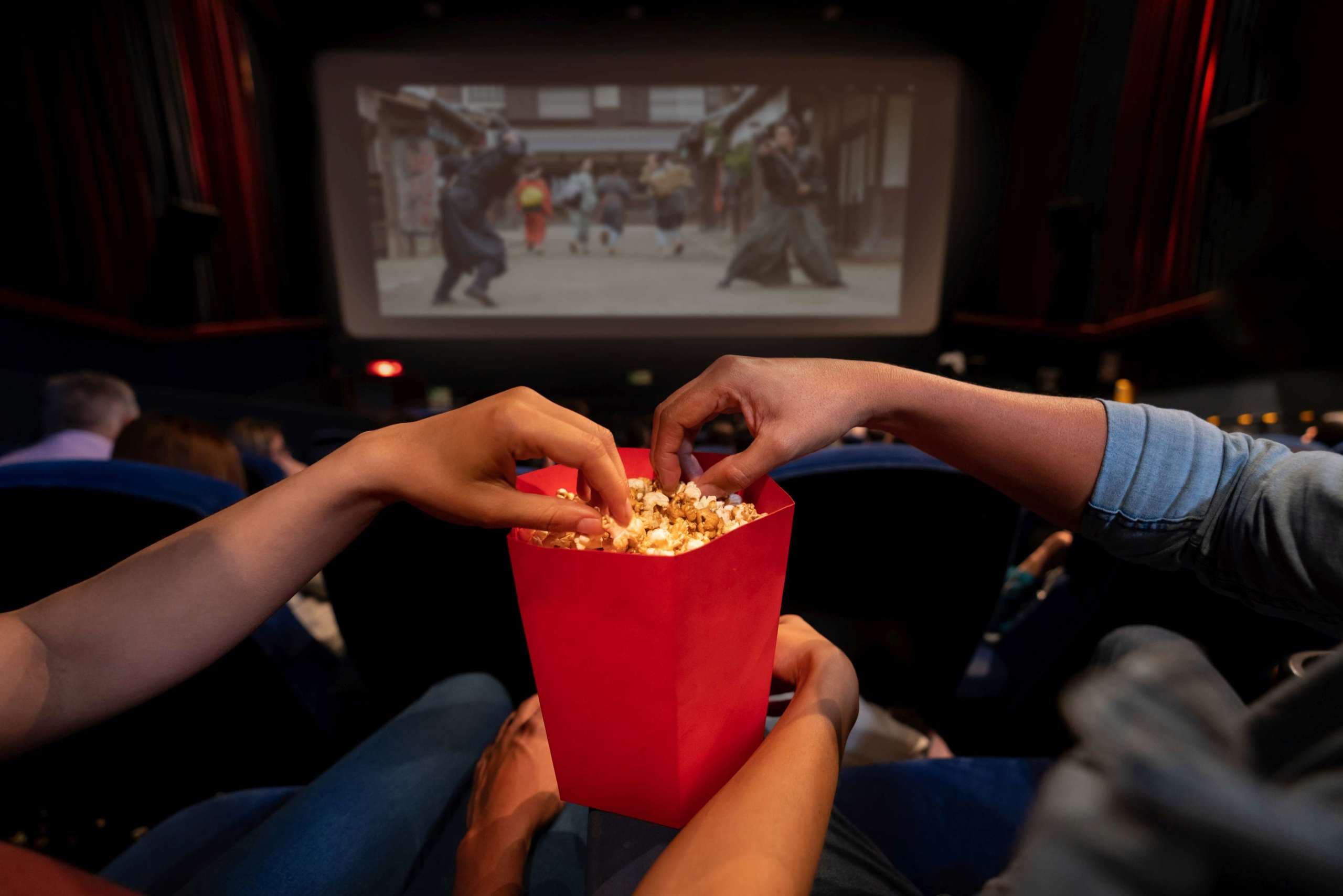 Nahaufnahme eines Paares im Kino, das Popcorn isst - Unterhaltungskonzepte. **BILD AUF DEM BILDSCHIRM GEHÖRT UNS**