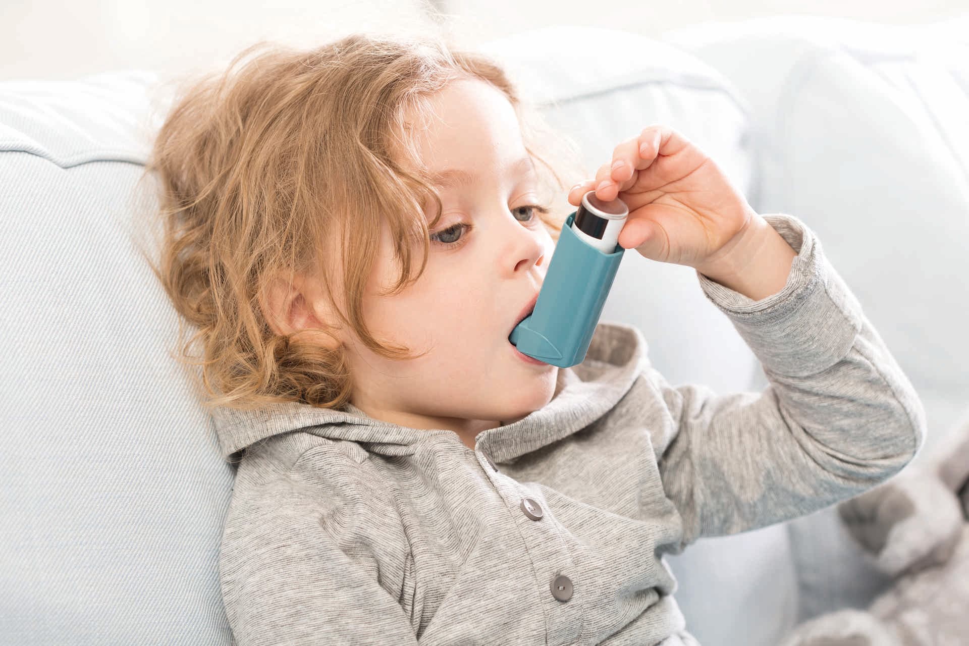 Kleines Kind, das sein Inhalationsgerät für Asthma verwendet