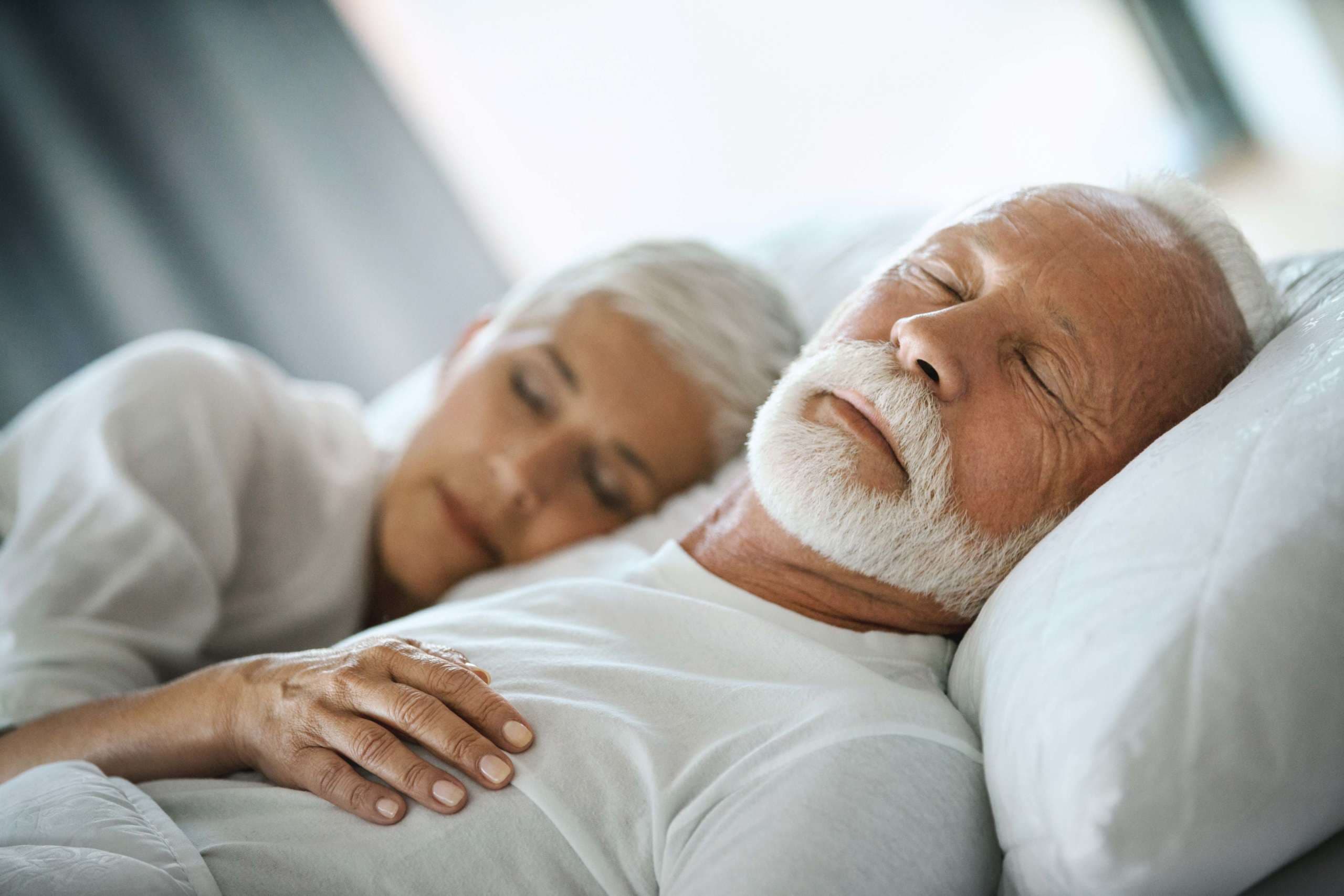 Nahaufnahme eines Paares Mitte der 60er Jahre, das spätmorgens in einem bereits hell erleuchteten Schlafzimmer schläft.