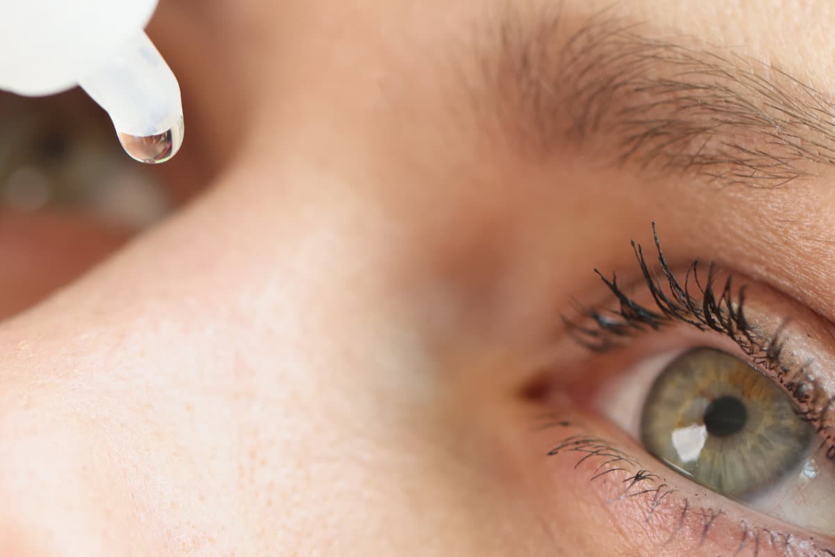 Close-up of middle age woman face and dripping eye drops. Treatment of conjunctivitis, allergy and dry eye syndrome.