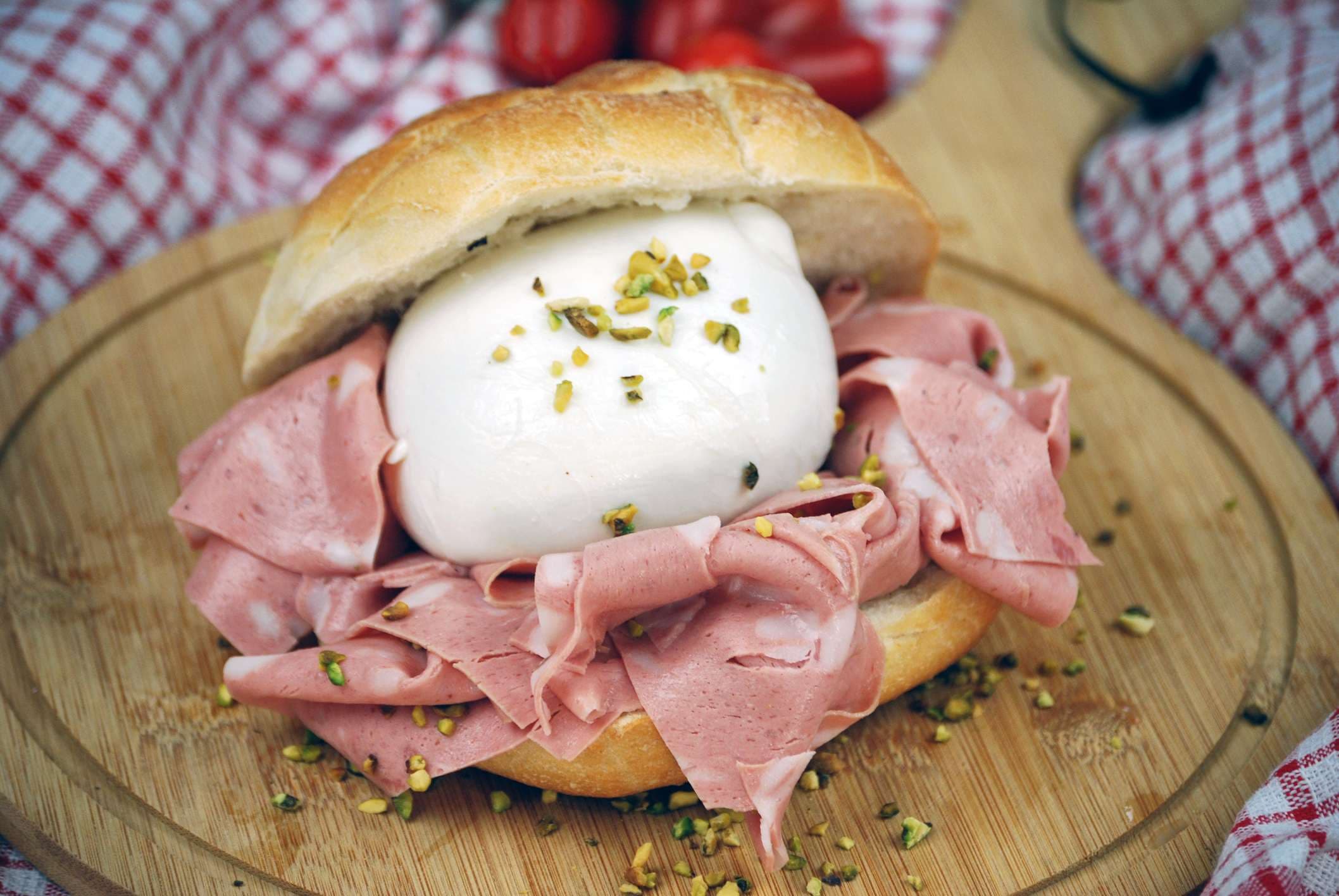 Sandwich mit Mozzarella, Mortadella und gehackten Pistazien auf einem Holzschneidebrett