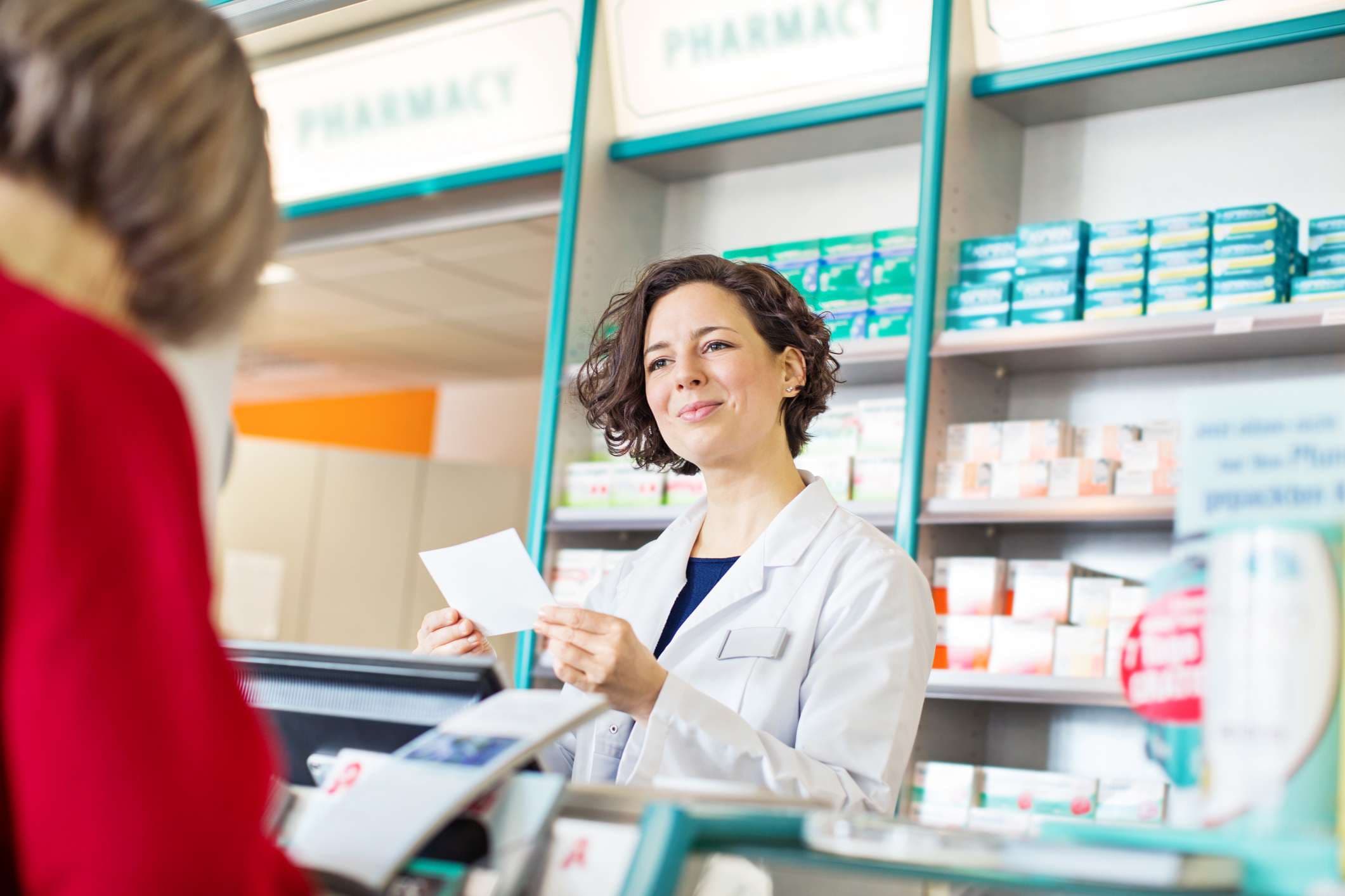 Glückliche Apothekerin, die Frauen beim Kauf von Medikamenten in der Apotheke hilft