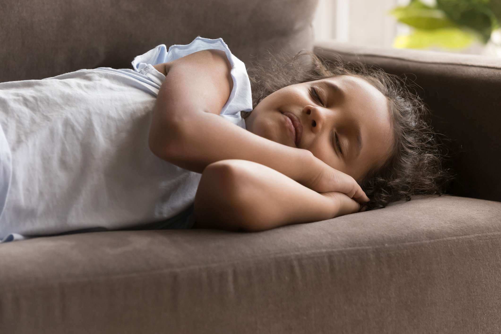 Kleines indisches Mädchen, das zu Hause auf Sofa schläft