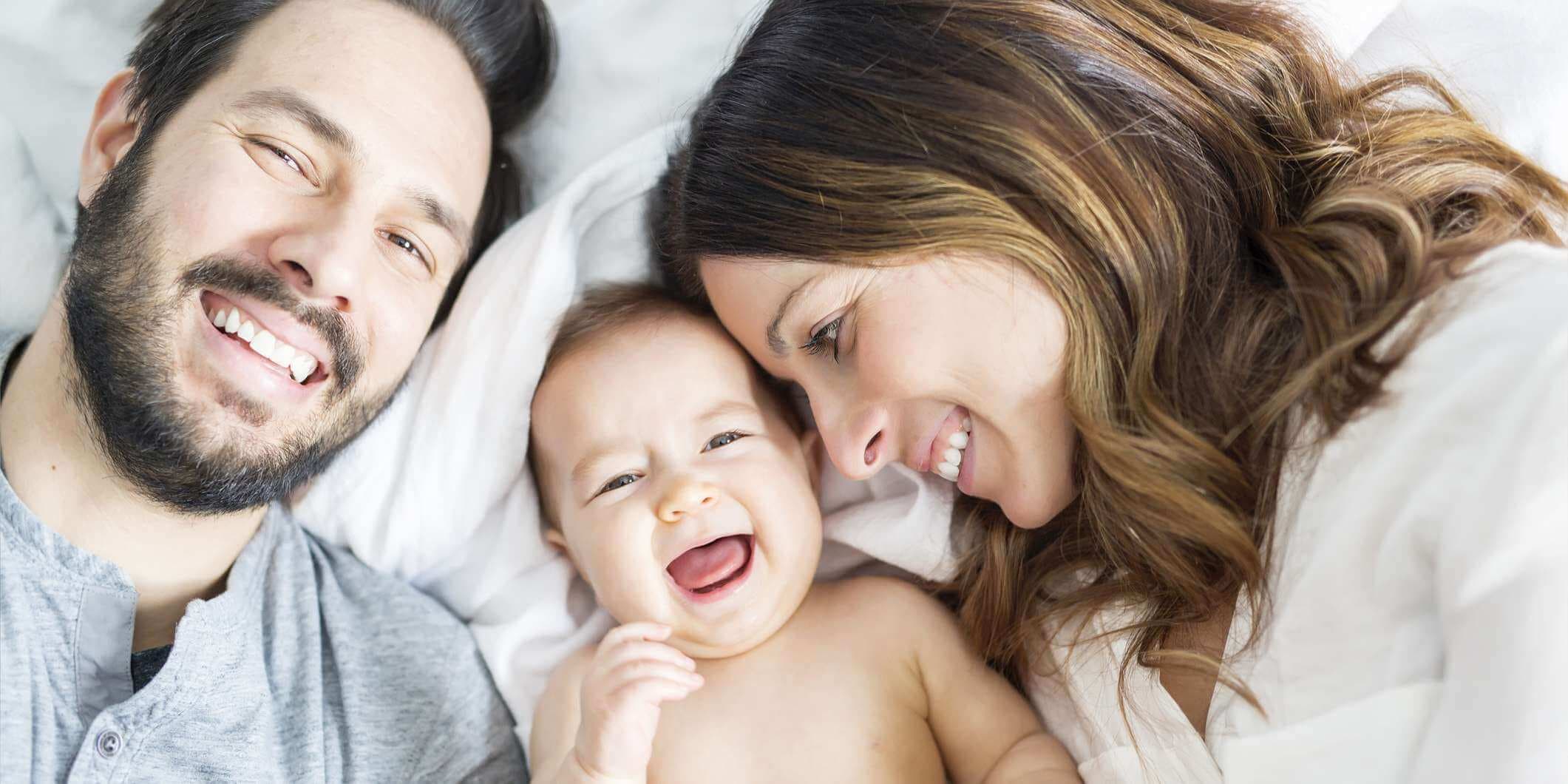 Ein Muttervater und ein Babykind auf einem weißen Bett.