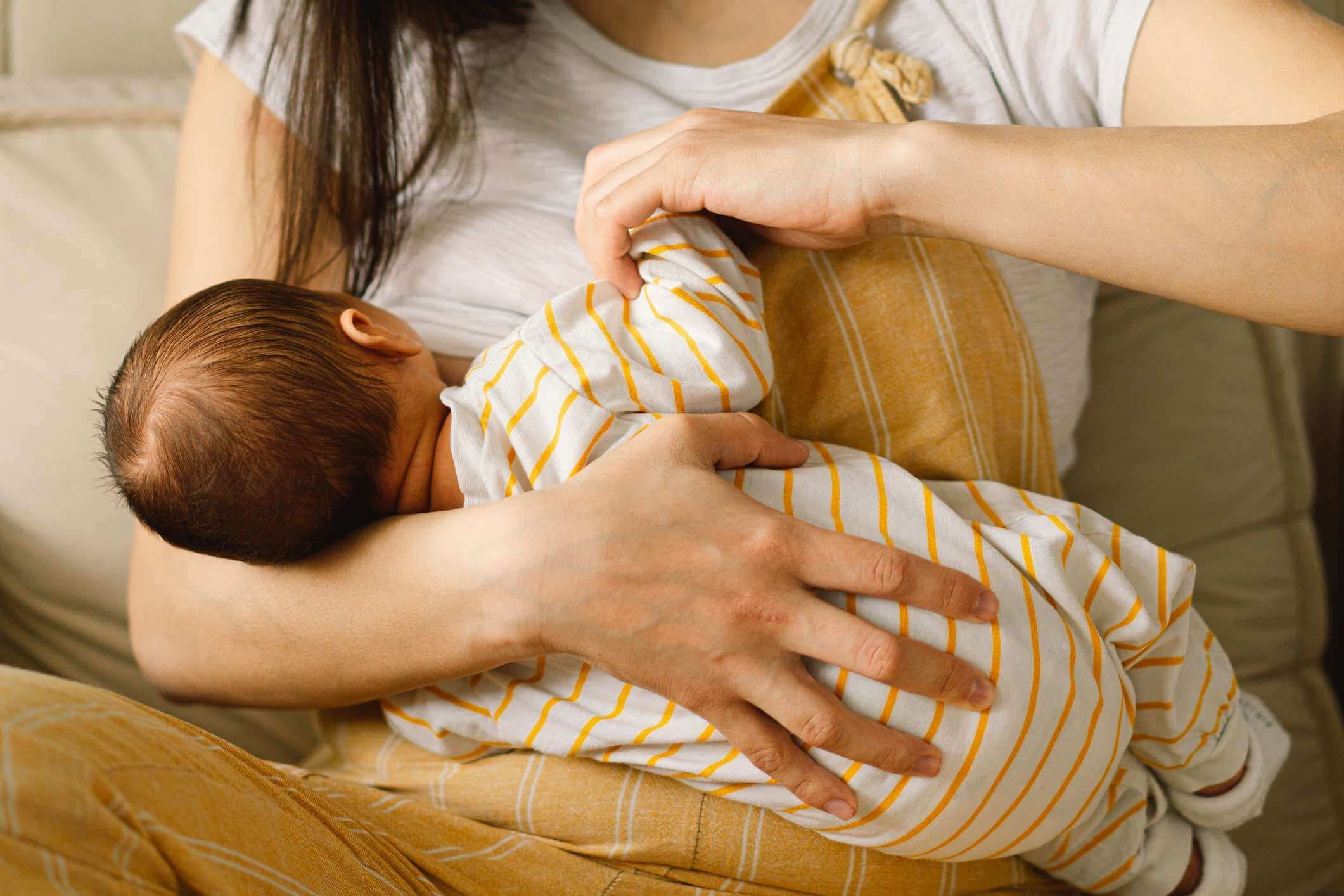 Neugeborenes Baby, das Milch von der Brust der Mutter saugt. Porträt von Mutter und stillendem Baby.