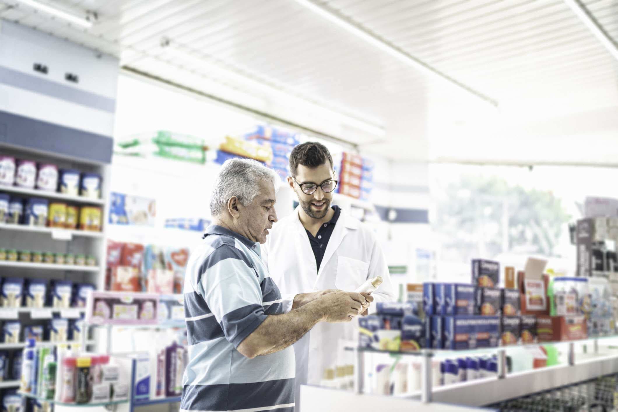 Junger Apotheker hilft einem Kunden, ein Medikament zu finden