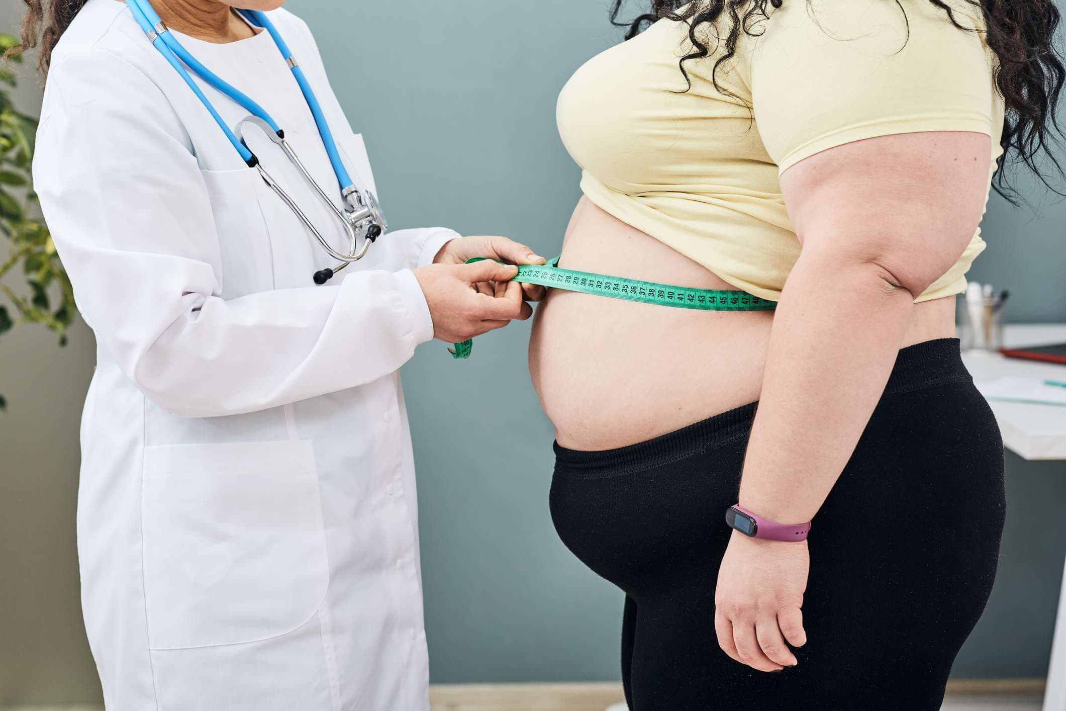 Fettleibigkeit, ungesundes Gewicht. Ernährungsberater untersucht die Taille einer Frau mit einem Messband, um eine Diät zur Gewichtsabnahme zu verschreiben