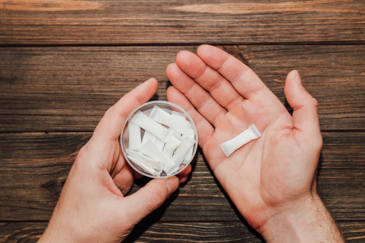 Männliche Hände halten eine Schachtel Snus mit Nikotinspinnen in der Hand.