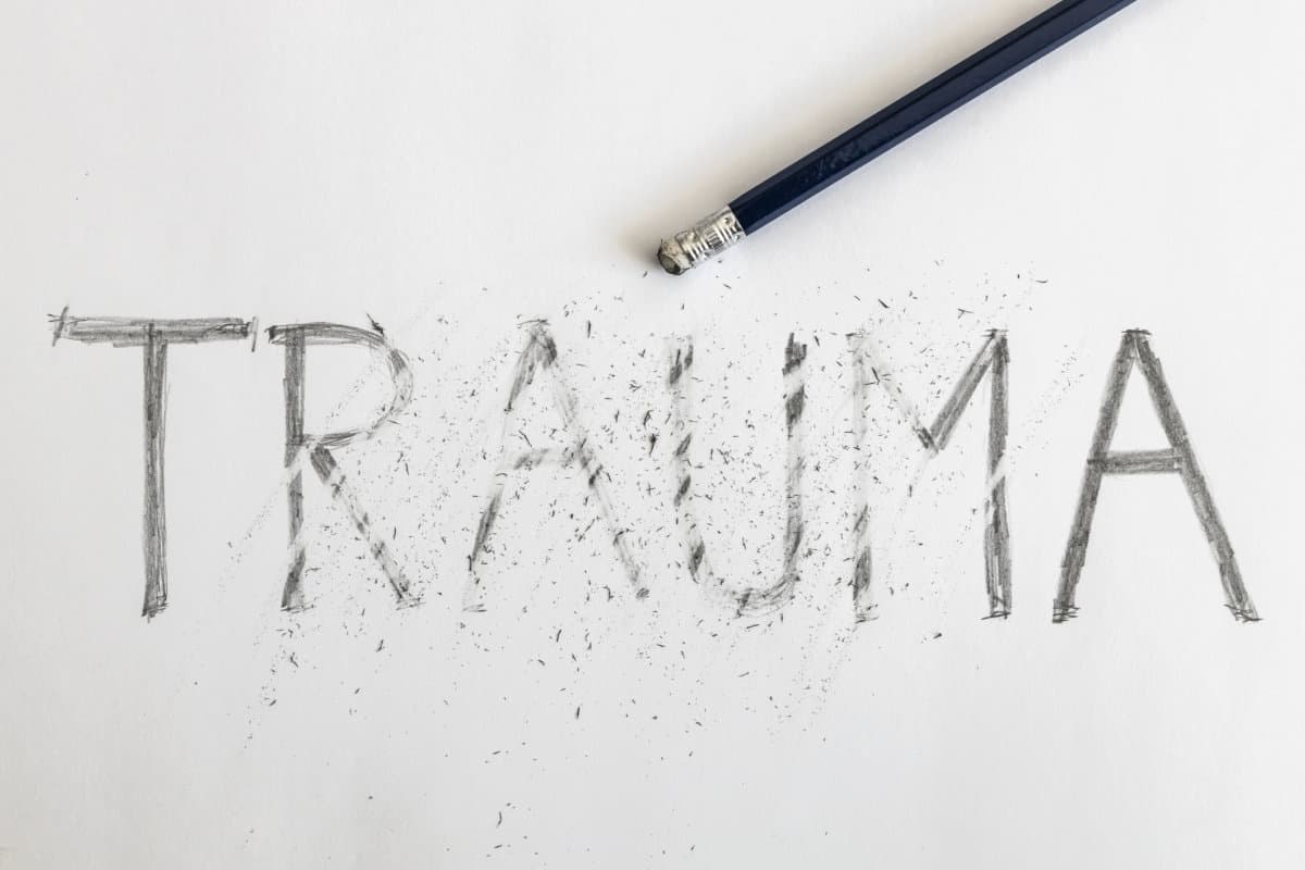 Erasing trauma. Trauma written on white paper with a pencil, partially erased with an eraser. Symbolic for overcoming trauma or treating trauma.