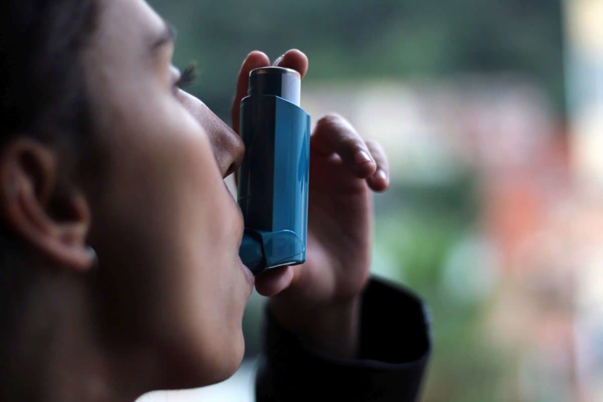 Health and medicine &#8211; Young girl using blue asthma inhaler to pr