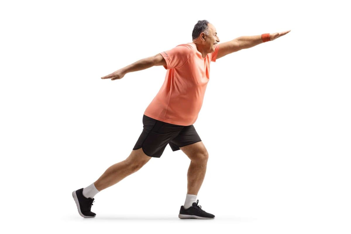 Full length shot of a mature man in sportswear exercising and stretching isolated on white background