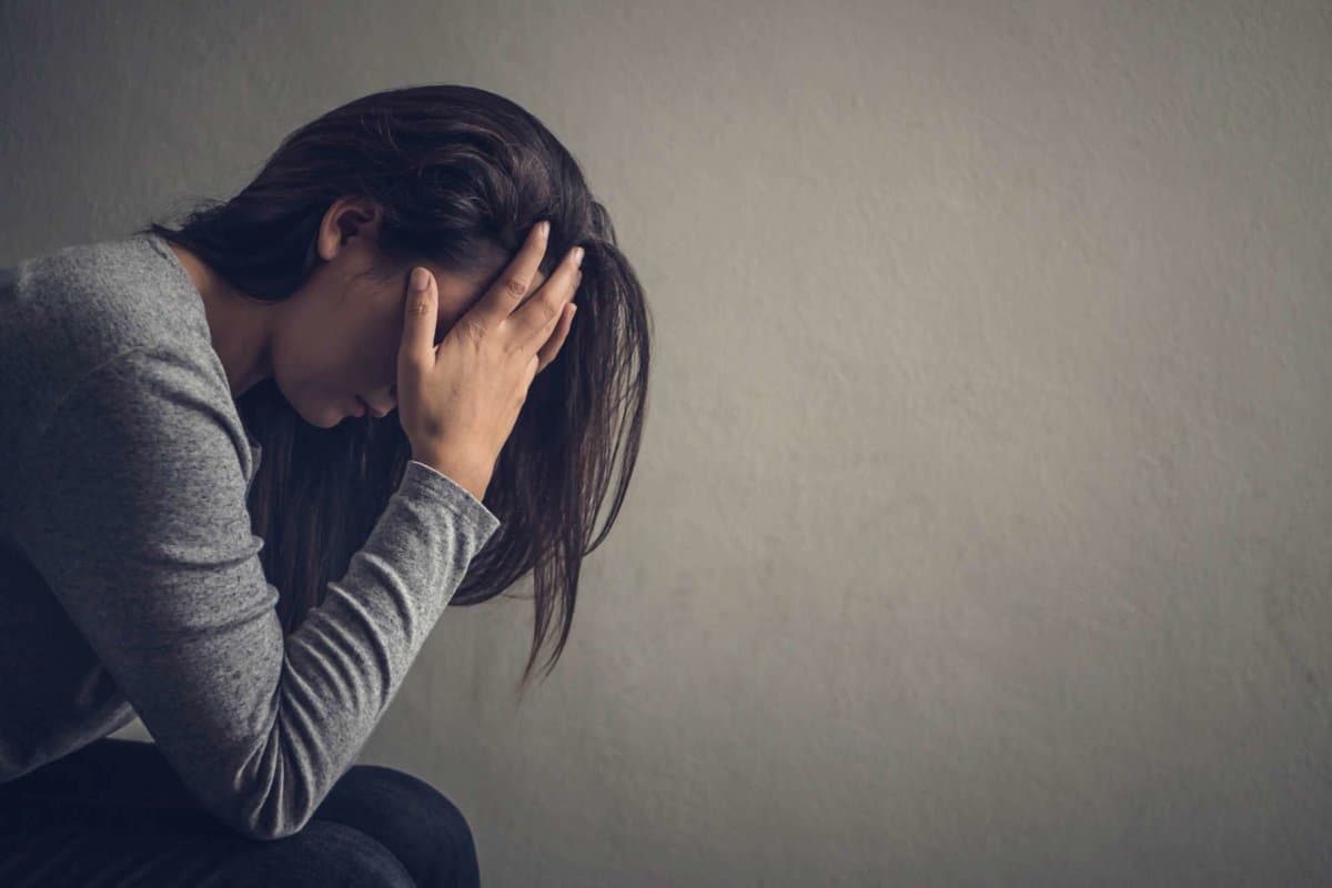 Depressed woman sitting on a chair in dark room at home. Lonly , sad, emotion concept.