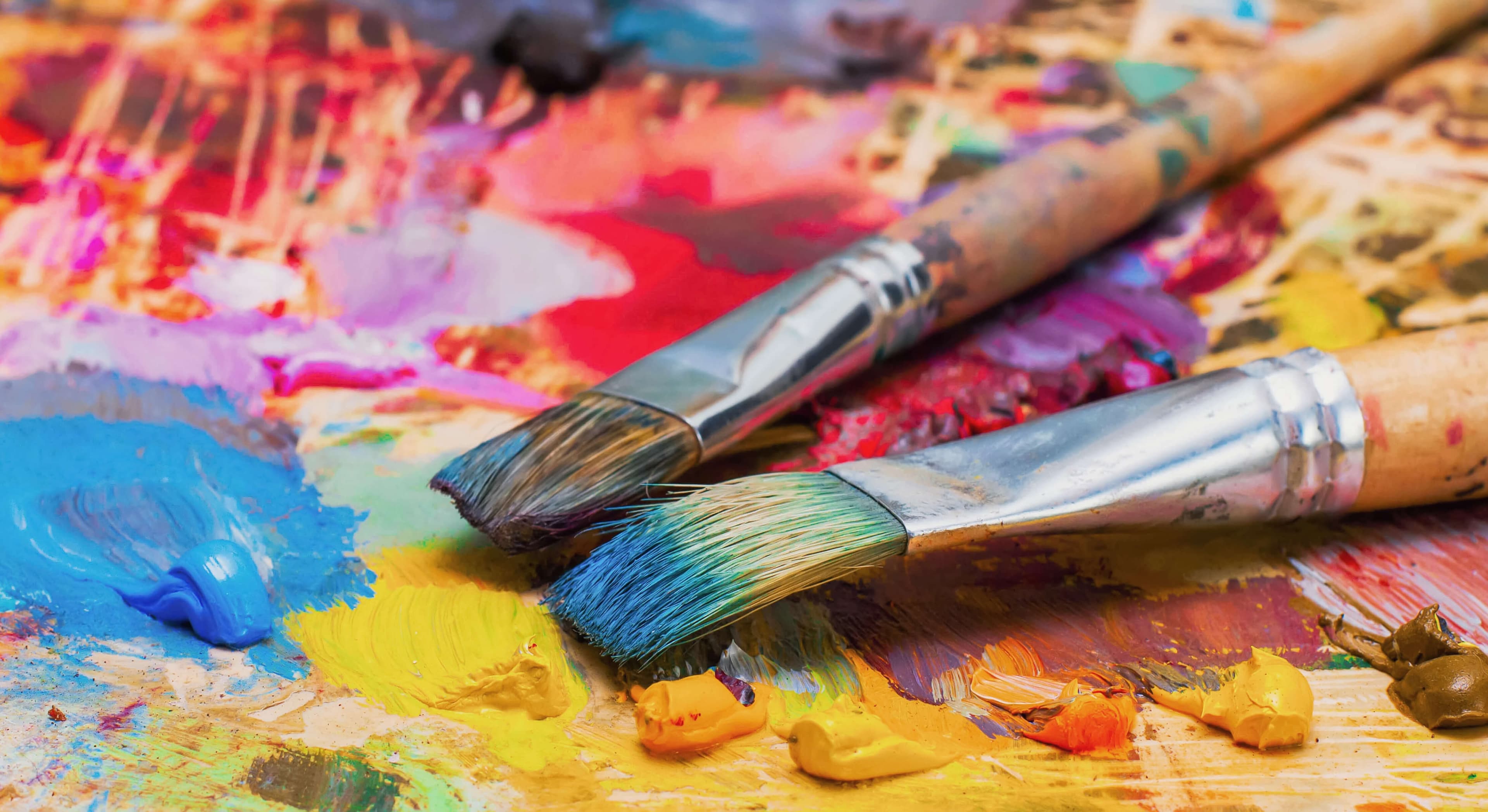 Used brushes on an artist's palette of colorful oil paint for drawing and painting