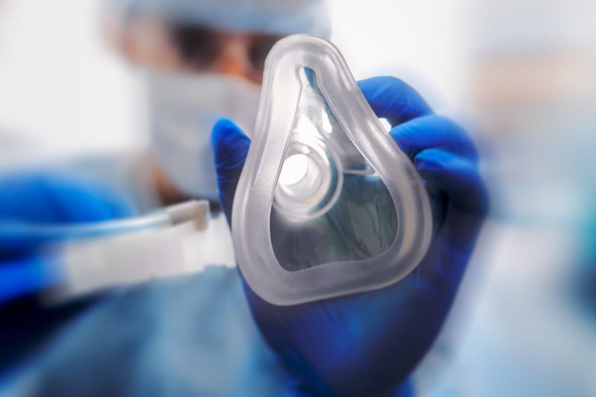 Doctor puts on oxygen mask to connect a patient losing consciousness to an artificial respiration device.