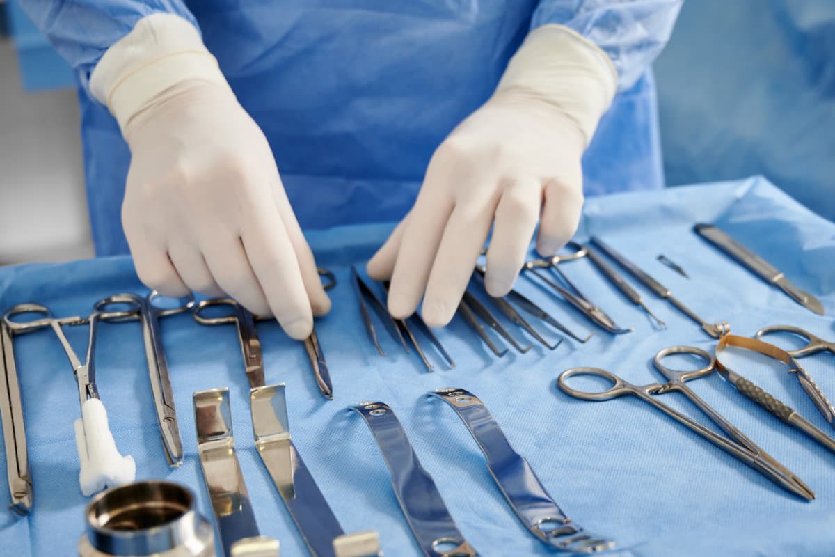 Doctor preparing instruments for plastic surgery in operating room.