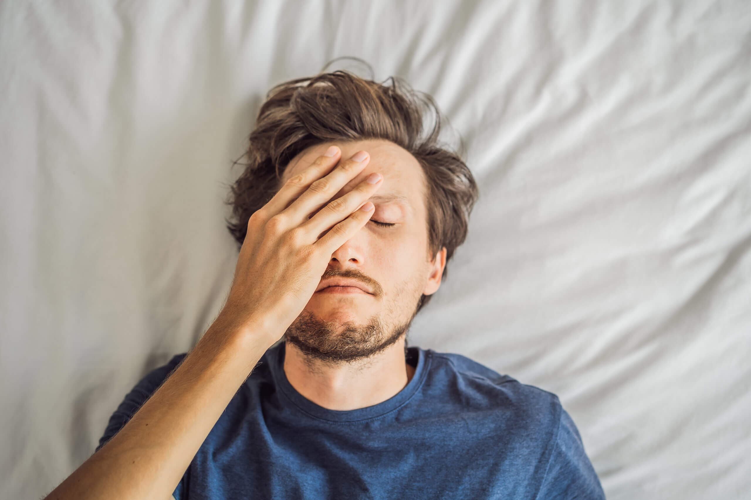 Jeune homme extrêmement fatigué allongé sur le lit, seul à la maison.
