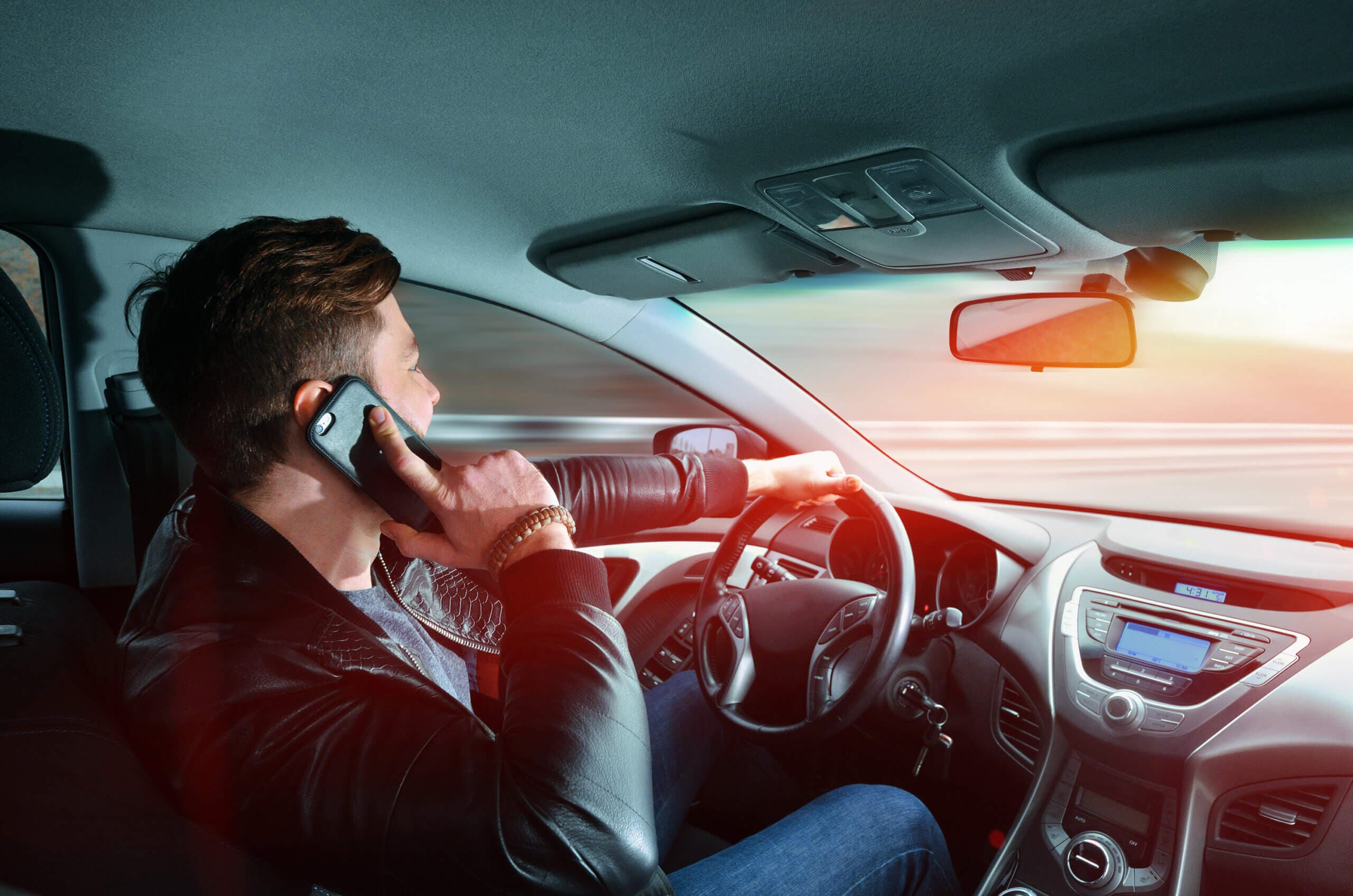 Ein Mann telefoniert mit dem Handy in einem Auto bei hoher Geschwindigkeit. Fahren mit hoher Geschwindigkeit. Autofahrt.
