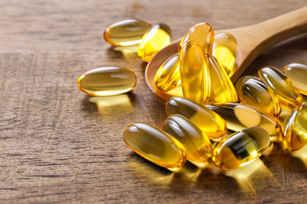 Fish oil capsules on wooden background, vitamin D supplement