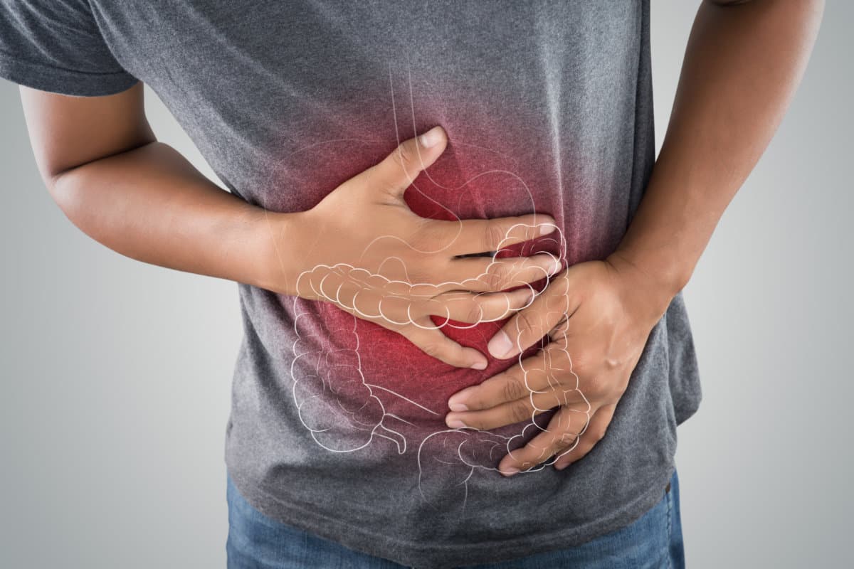 The photo of large intestine is on the man&#8217;s body against gray b