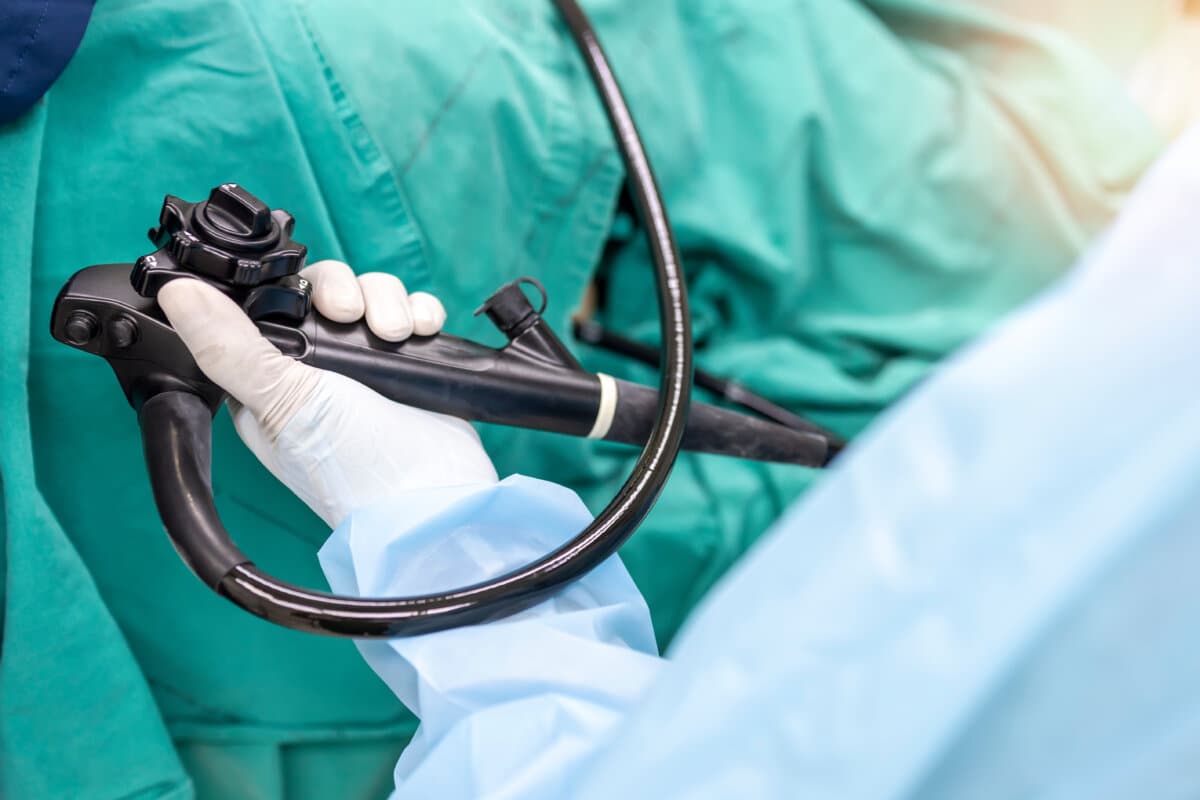 A doctor or surgeon in a light blue protective gown did a colonoscopy or gastroscopy inside operating theatre in the hospital.EGD technology for cancer screening.Blur green background and foreground.