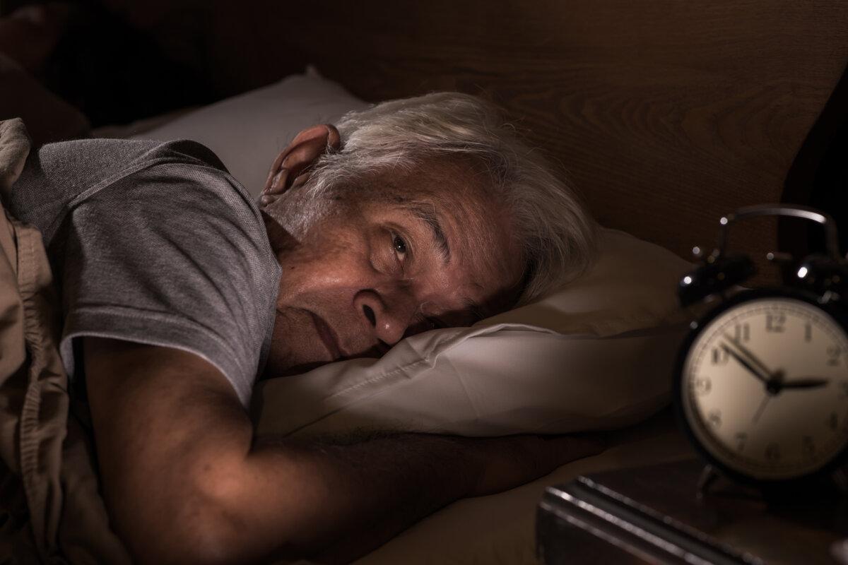 Depressiver älterer Mann liegt im Bett und kann wegen Schlaflosigkeit nicht schlafen