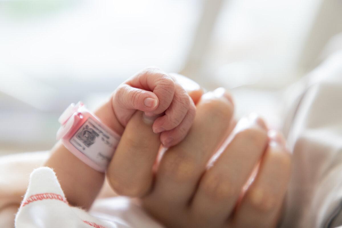 Neugeborenes Baby hält den Zeigefinger der Mutter in der Hand. Konzept: Frühgeburt oder