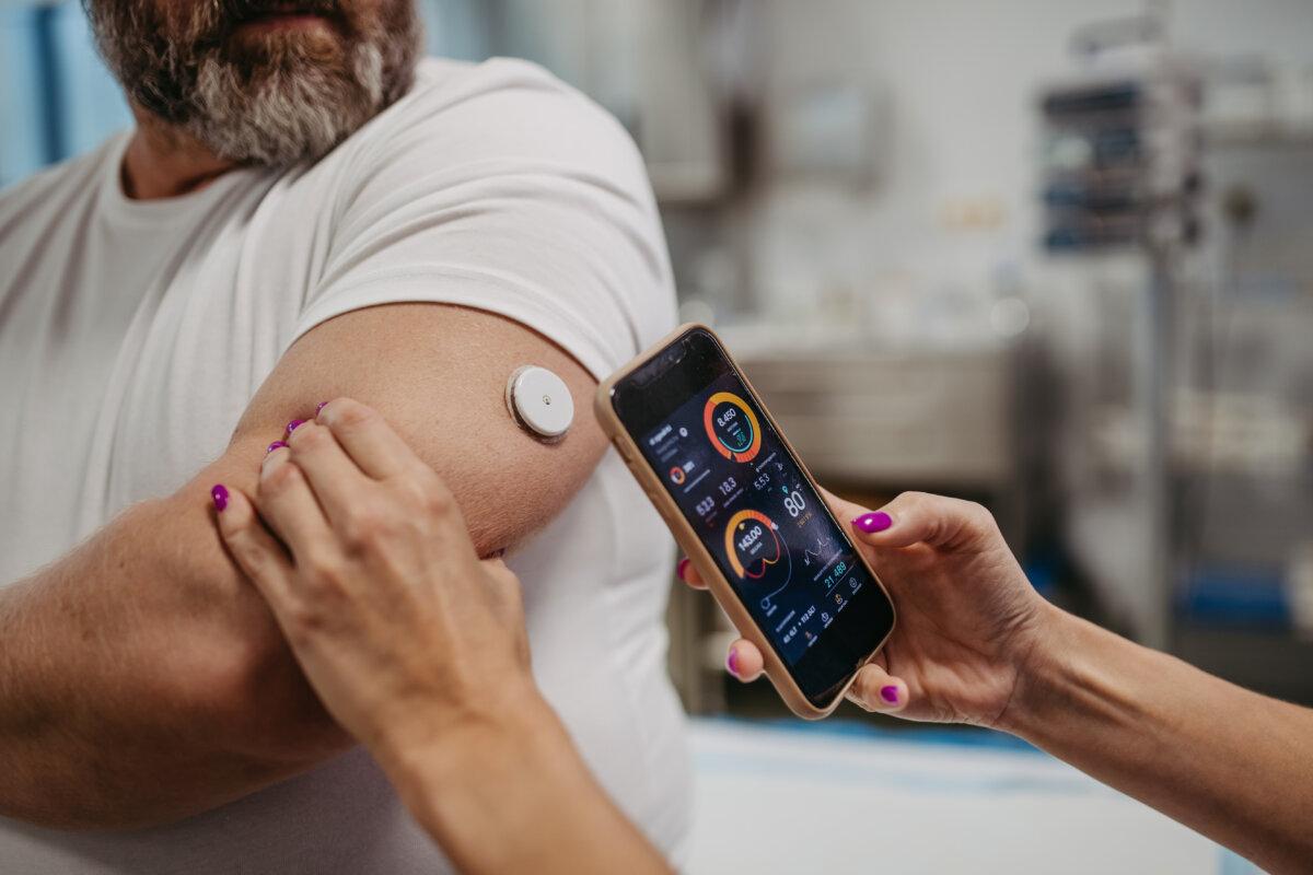 Arzt verbindet kontinuierlichen Glukosemonitor mit Smartphone, um Blutzuckerspiegel in Echtzeit zu überprüfen.