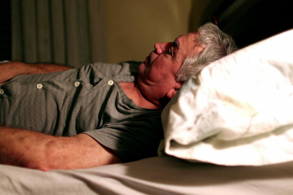 Alter Mann liegt nachts im Bett und leidet an Schlaflosigkeit und kann nicht schlafen