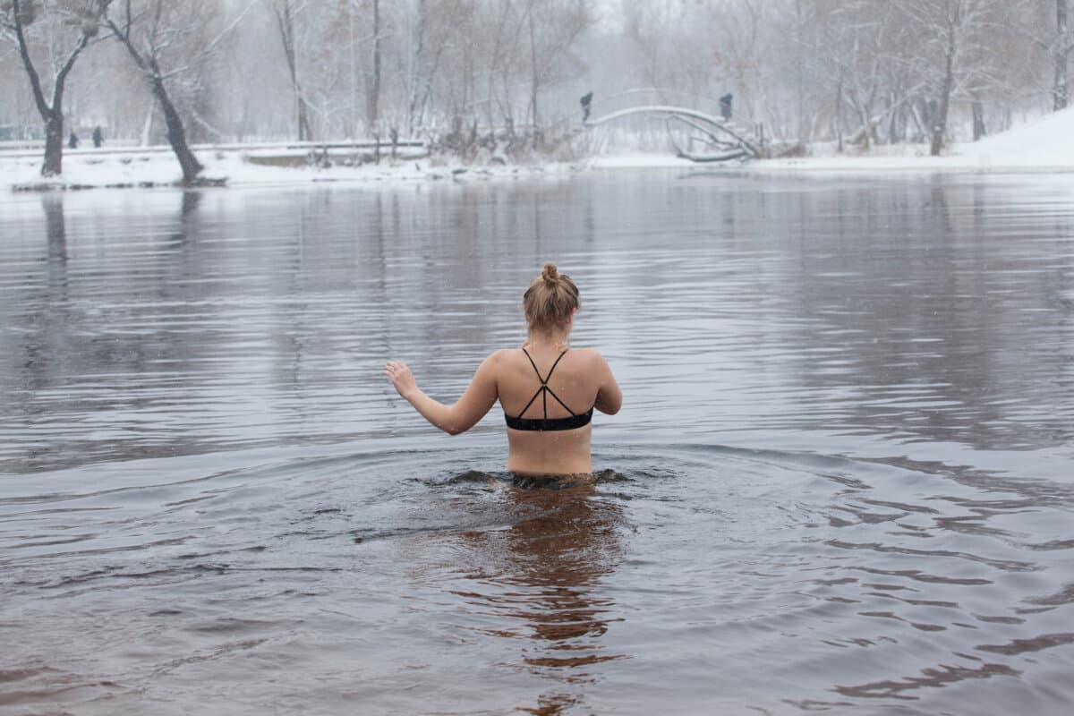 Eine Frau geht im Winter in einem Fluss schwimmen.