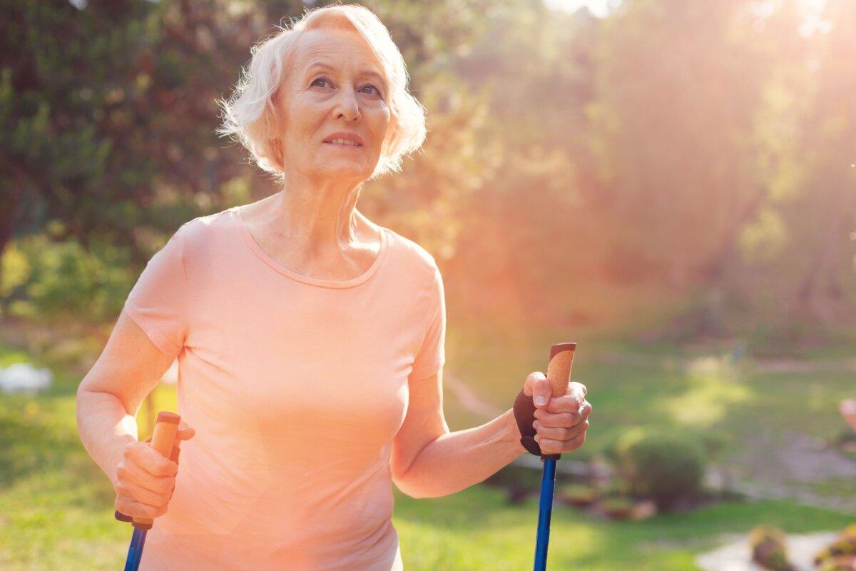 Eine ältere Frau mit Nordic Walking Stöcken.