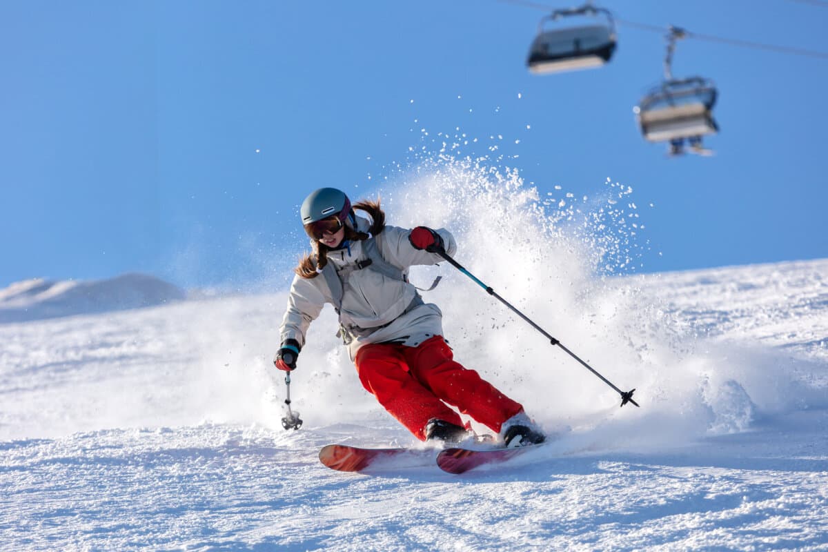 Ein Mädchen auf der Skipiste fährt bergabwärts.