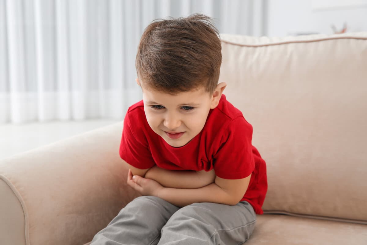 Kleiner Junge leidet unter Übelkeit im Wohnzimmer