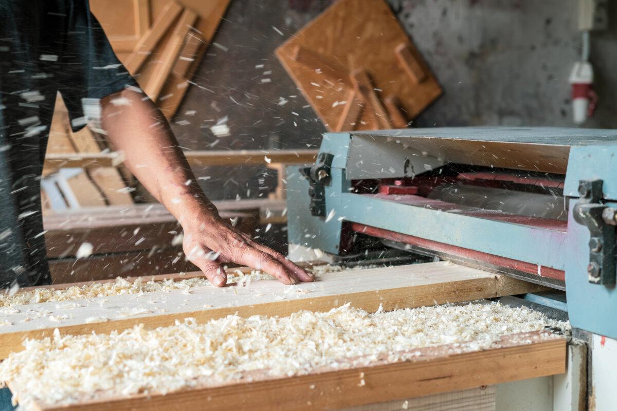 Automatische Schleifmaschine für Holzplatten. Überall wird Holzstaub verstreut.