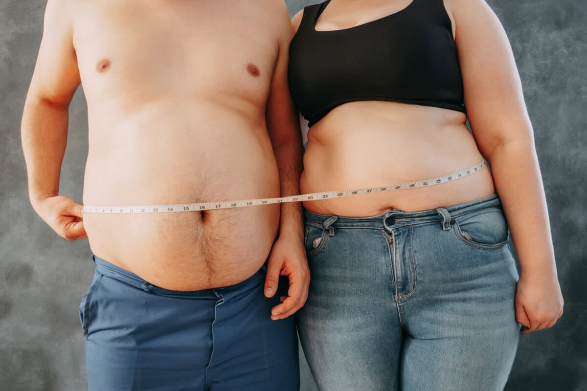 Übergewichtiges Paar steht zusammen und wickelt Maßband ein. Diät, Familiengewichtsverlust und Gesundheitskonzept