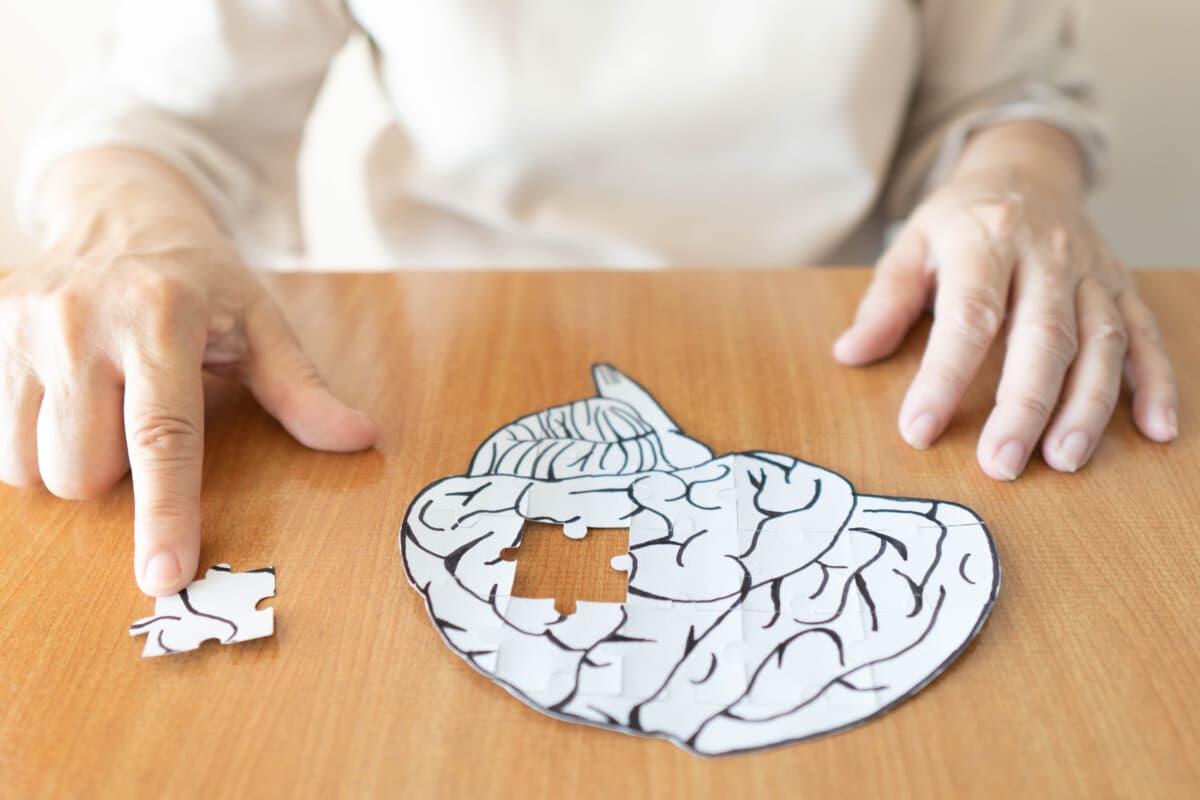 Ältere Frau Hände setzen fehlende weiße Puzzleteil tun