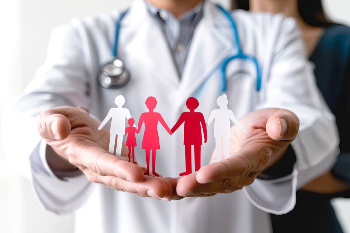 Nahaufnahme der Hände des Arztes, die einen Papierausschnitt der Familie halten und damit Gesundheitsfürsorge und
