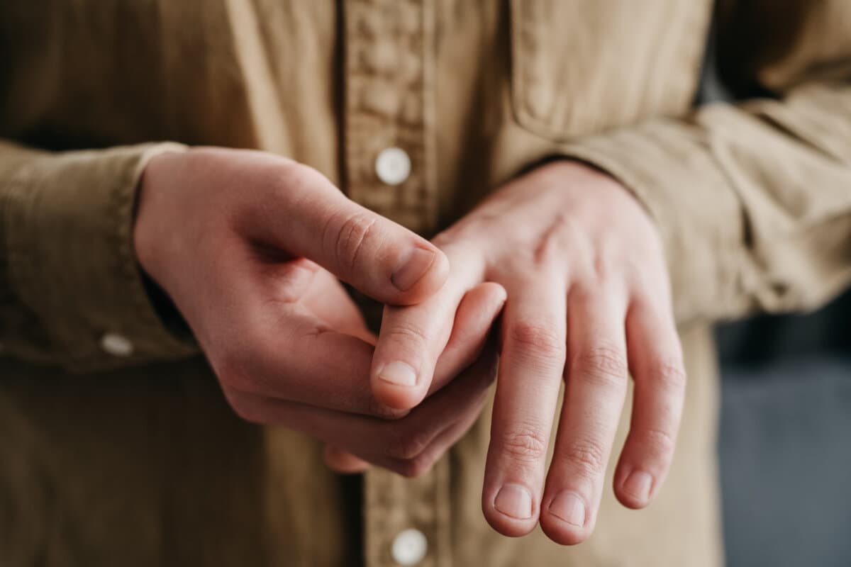 Nahaufnahme eines jungen, ungesunden Mannes mit Arthritis in den Fingern.