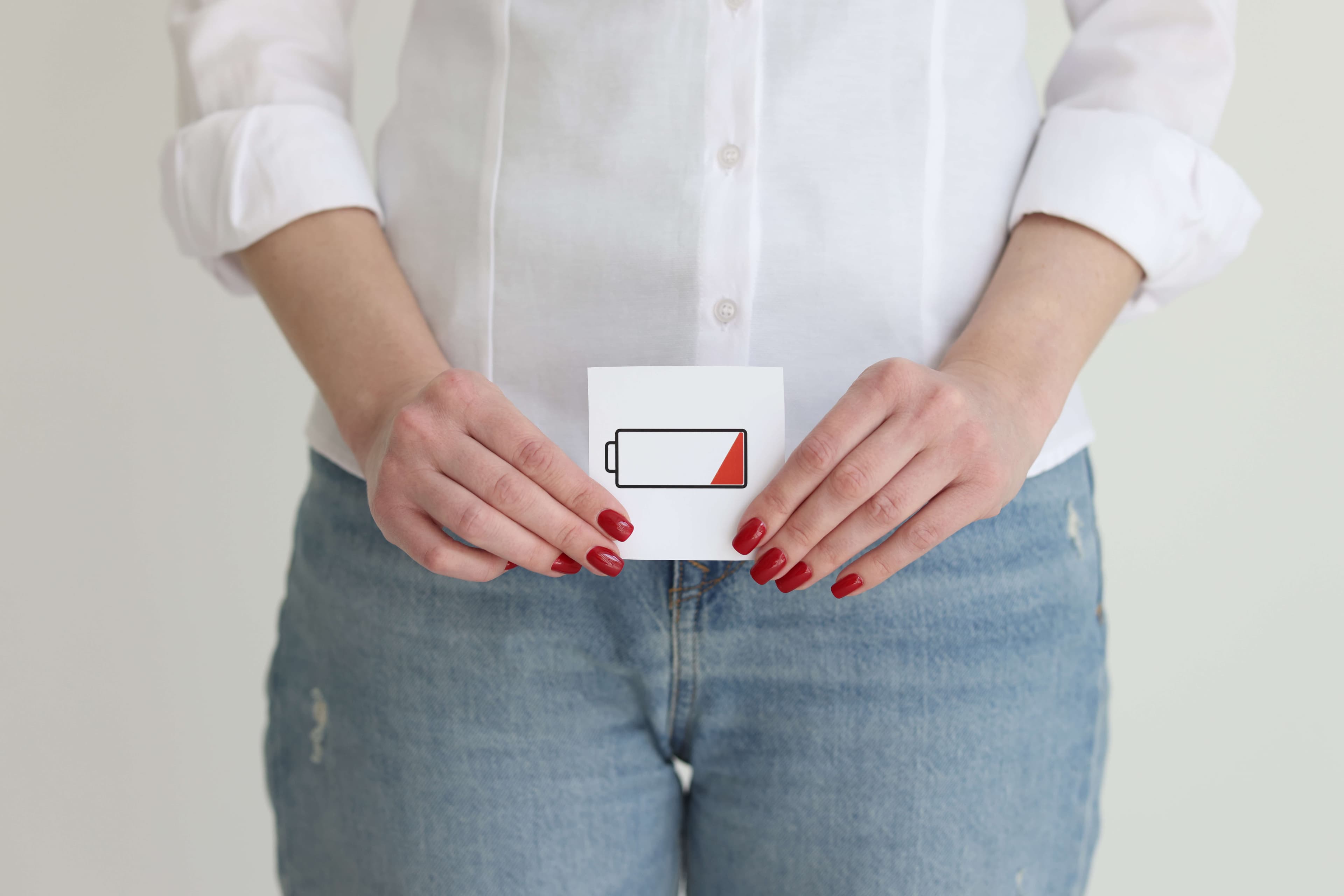 Frau in Jeans und Hemd zeigt Bild einer entladenen Batteriezelle