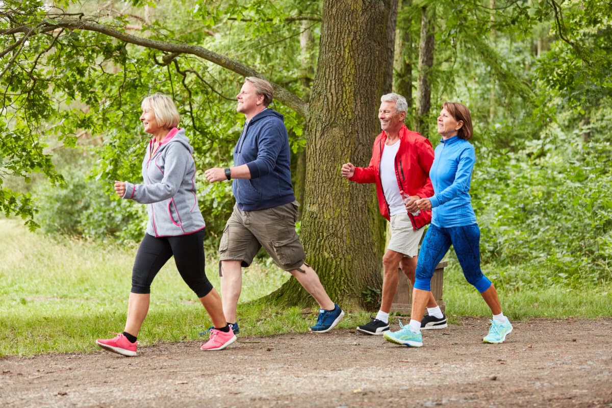 Seniorengruppe beim Spazierengehen oder Walking als Fitnesstraining in der Natur