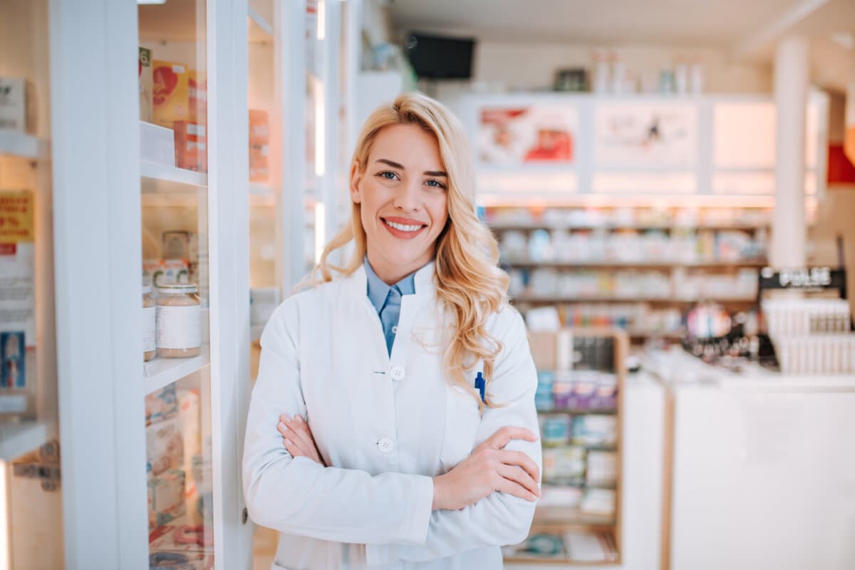 Fröhliche Apothekerin Chemikerin steht in Apotheke Drogerie