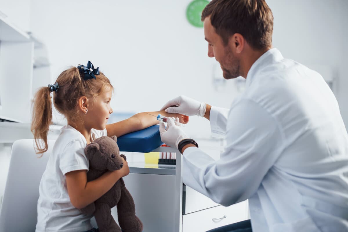 Blutentnahme. Kleines Mädchen mit ihrem Teddybär ist mit dem Arzt in der Klinik.