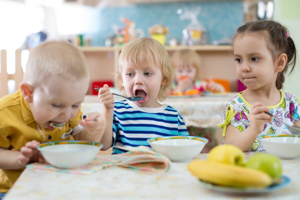Lustige Kindergruppe beim Essen in der Kindertagesstätte