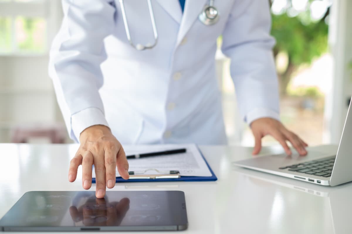 Arzt, der ein digitales Tablet verwendet, um im Krankenhaus Informationen zur Krankengeschichte des Patienten zu finden.