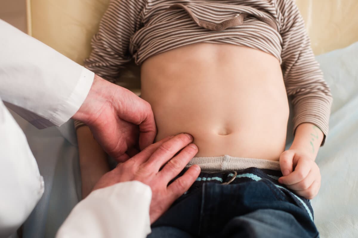 Kid doctor touch belly of small patient with fingers. Pediatrician check stomach of child.