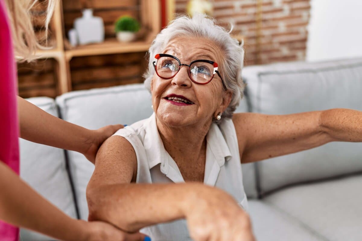 Senior grey-haired woman patient supported for nurse and walker at geriatric