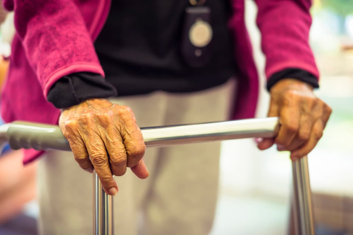 Old elderly Indian Asian woman walking with a Zimmer frame or walking frame, UK