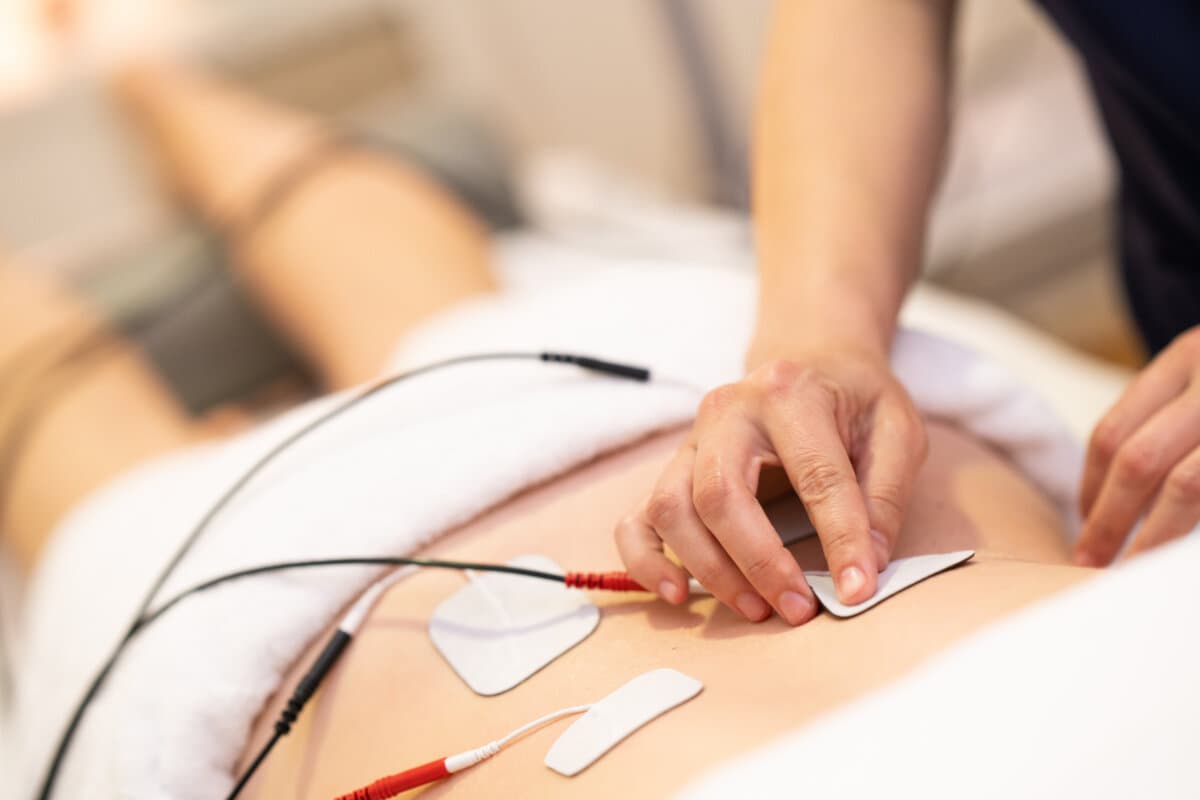 Physiotherapist applying electro stimulation in physical therapy to a young woman.