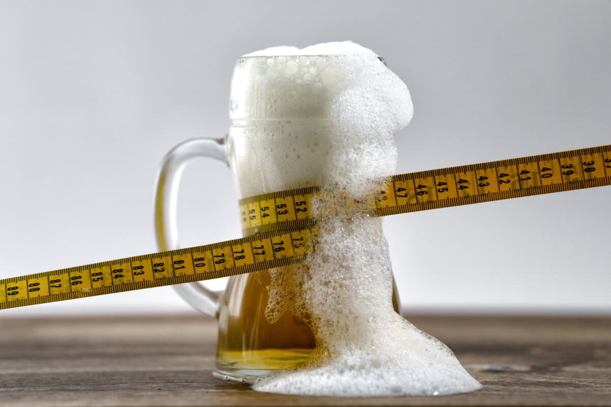 Tape measure wrapped around a glass of fresh draught beer.