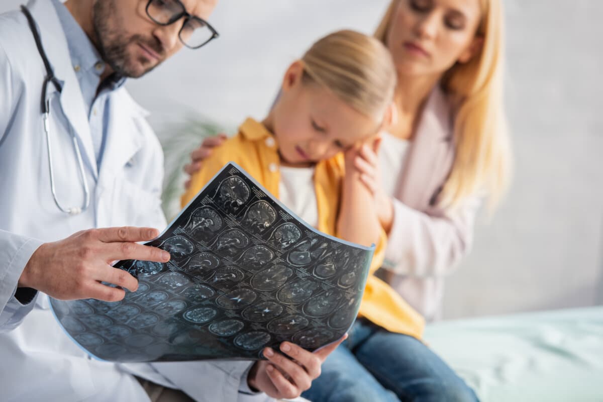 Mri scan in hands of blurred pediatrician near sad kid and woman in clinic