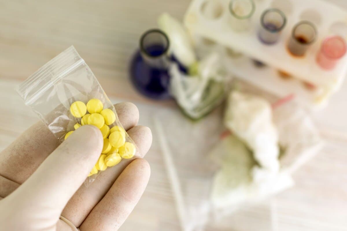 Chemiker hält eine Probe von Tabletten unklarer Herkunft hoch.
